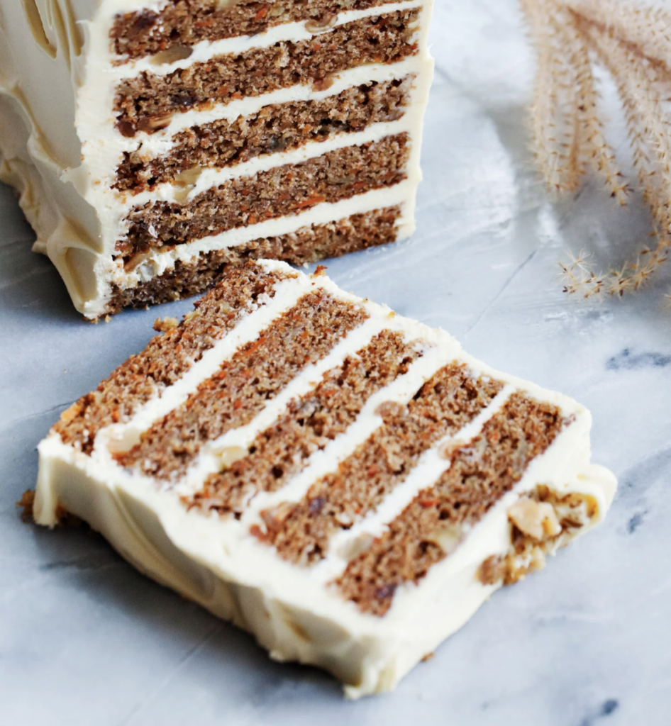 Sliced carrot cake with five decadent layers of white icing.